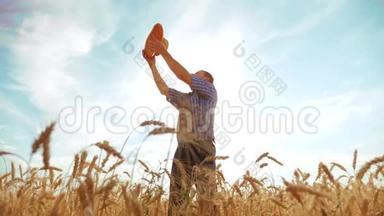 <strong>老农</strong>夫剪影面包师拿着一个金色的面包和面包在成熟的麦田对抗蓝色的生活方式天空。 慢慢慢慢